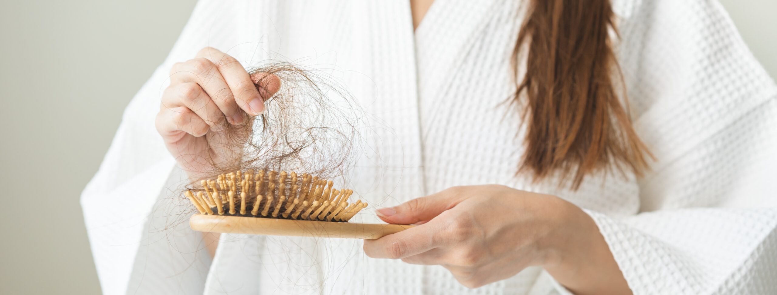 Persona con expresión de estrés tocando su cabello, ilustrando la relación entre salud emocional y pérdida capilar